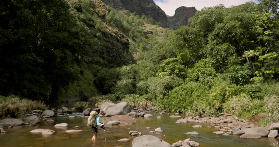 Woman hikes through a rocky stream