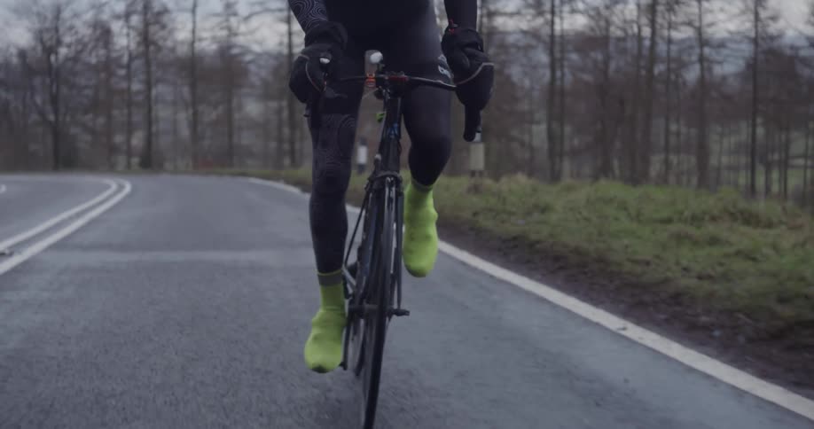 A rider stands as he pedals his bike up a hill