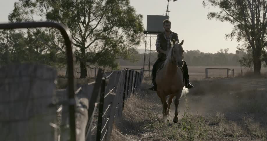 A man rides a horse near a fence
