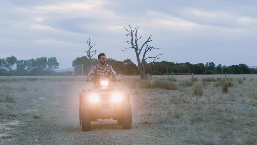 Man drives a four wheeler in a grassy pasture