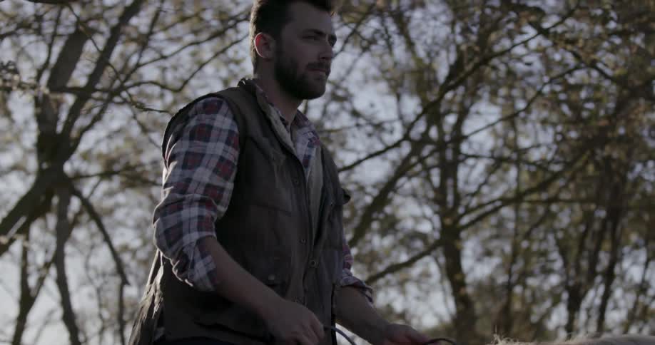 A man is riding a horse on a windy day