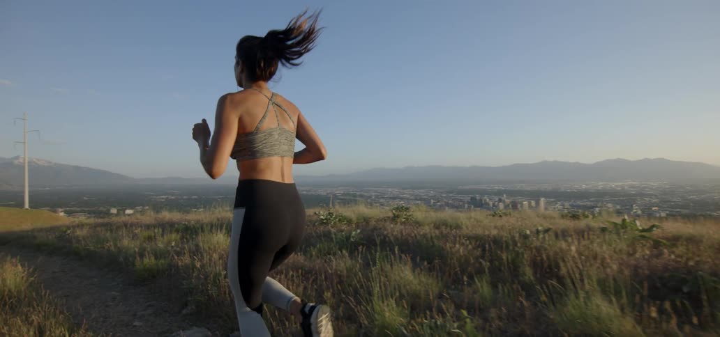 A woman jogs along a path atop a hill