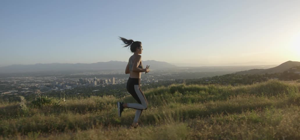 A woman is running on the grass on a sunny day