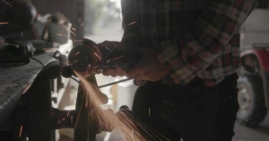 Person grinding a piece of metal in a workshop