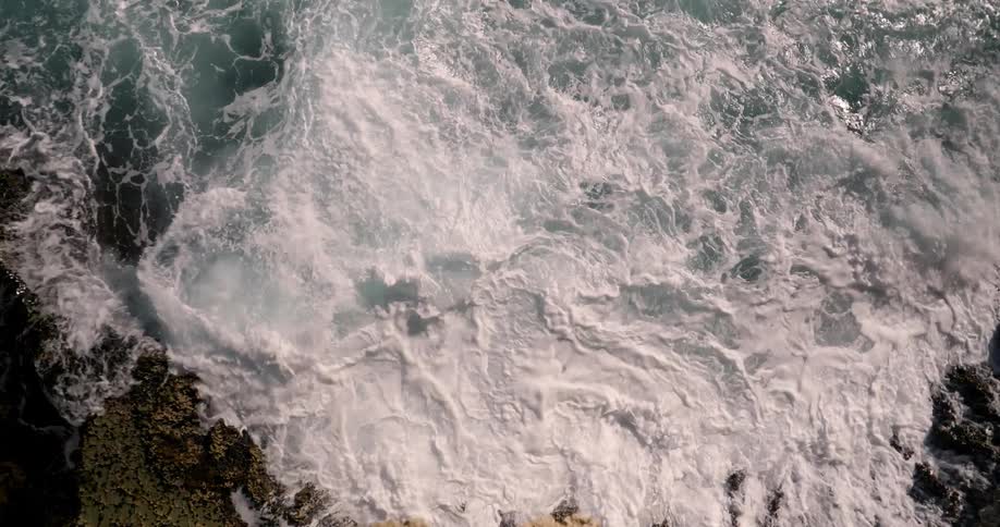 Ocean waves splash and foam as they break on the rocks