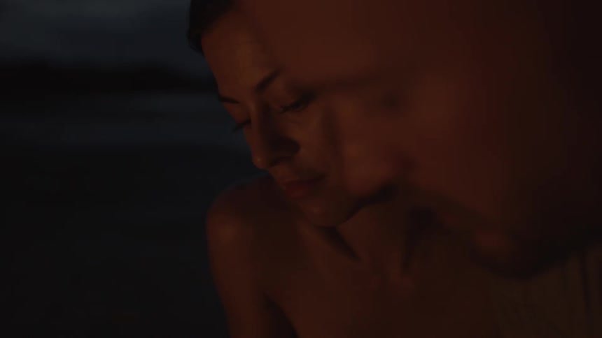 A man and woman talk while sitting outside at night