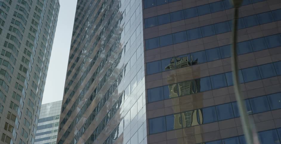 Buildings and sunlight reflect on the glass of city skyscrapers