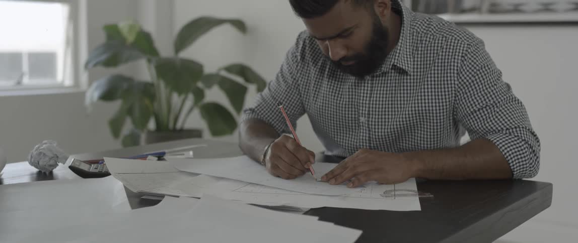 A man draws on paper at a work table