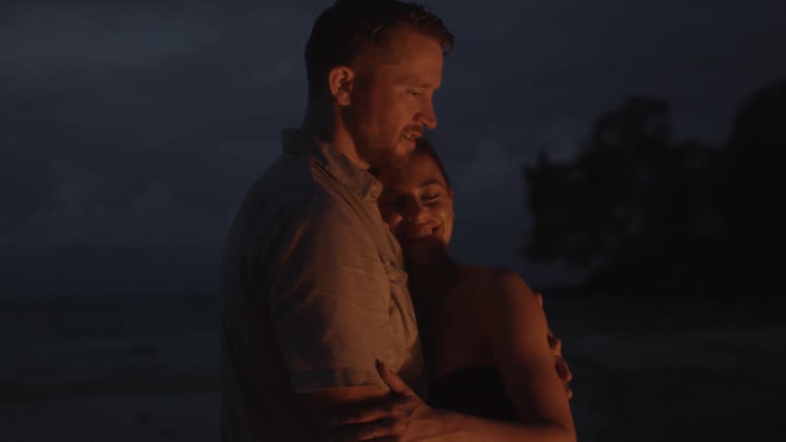 A couple hug near a fire