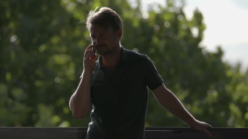 A man talks on the phone outside on a sunny day