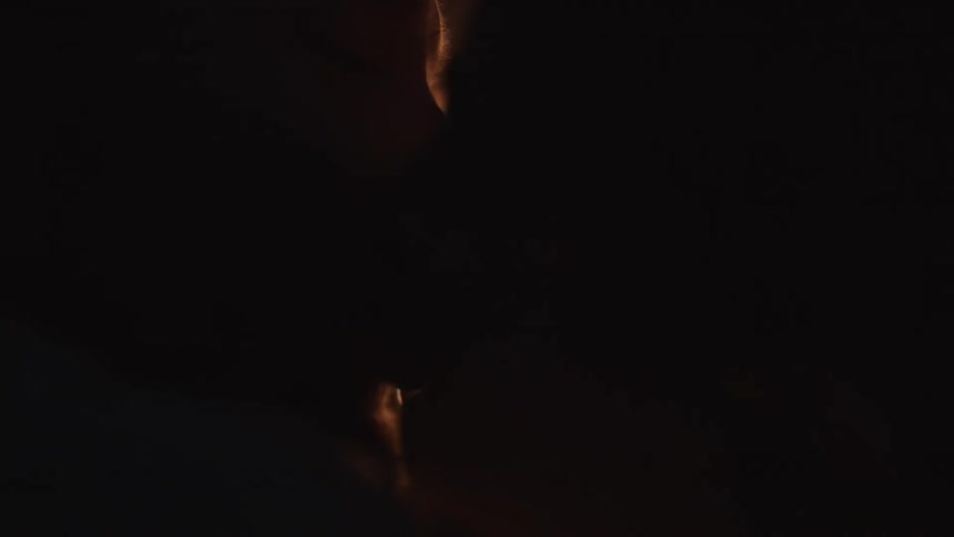 A man and woman kiss by a campfire at night