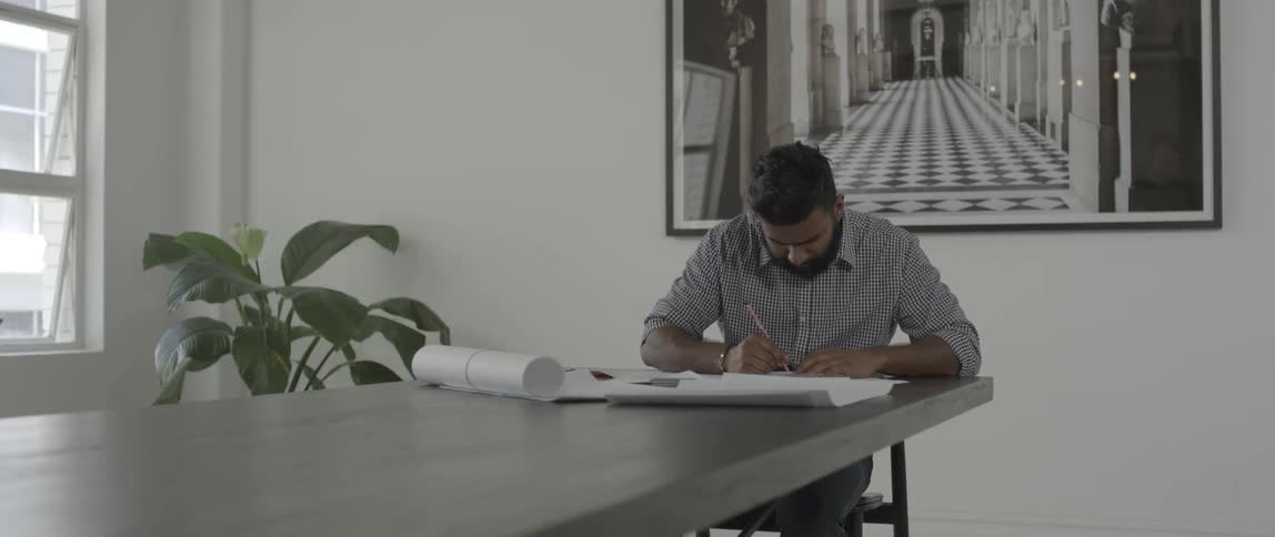 A man is sitting at a conference table working on papers