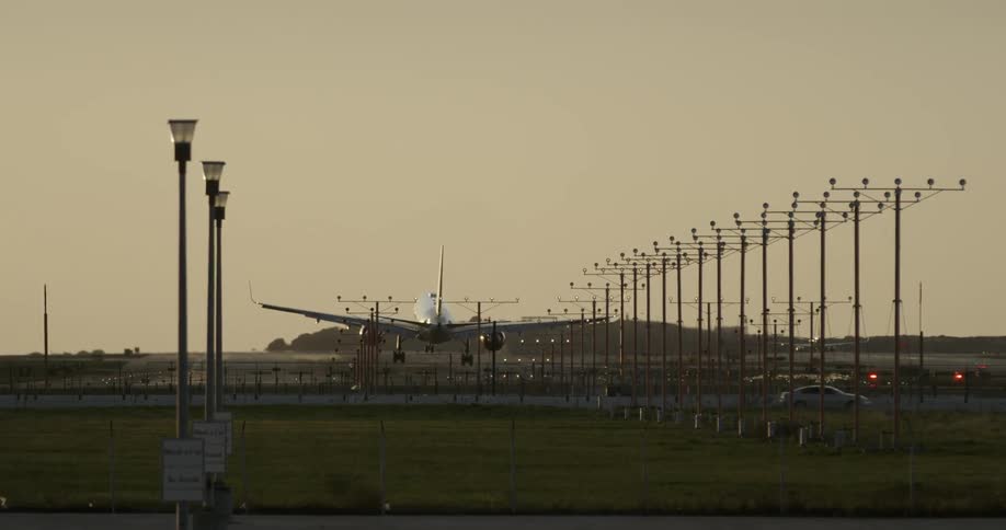 An airplane flies low over a highway while landing on the runway