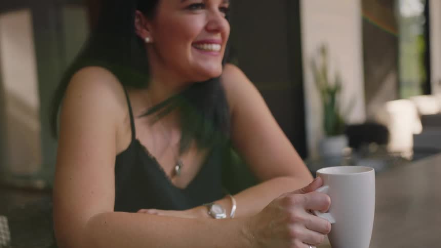A woman is smiling outside with a mug in her hands