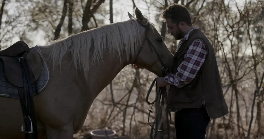 A man leans close petting his horse