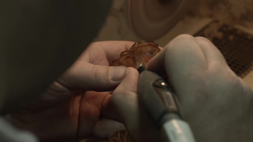 A person carves a yellow glass flower