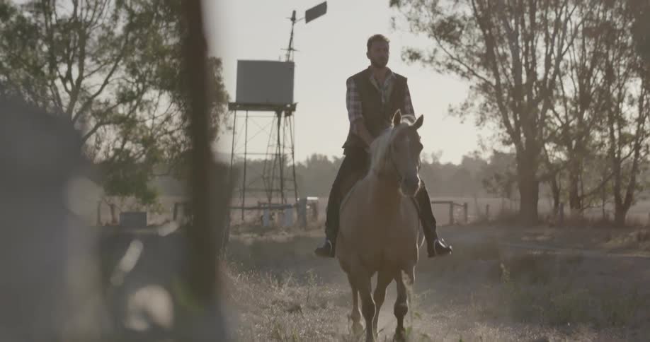 Man rides horse near fence