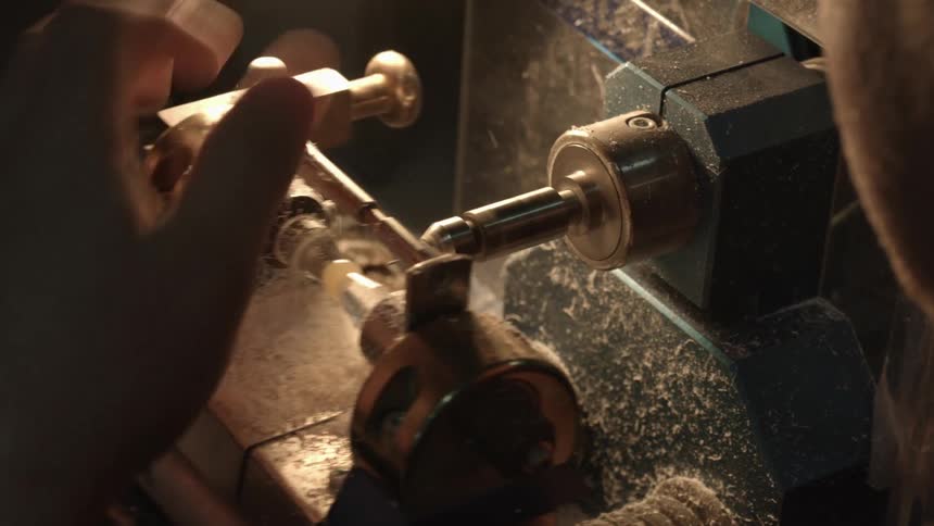 A person uses a piece of machinery to drill a small object