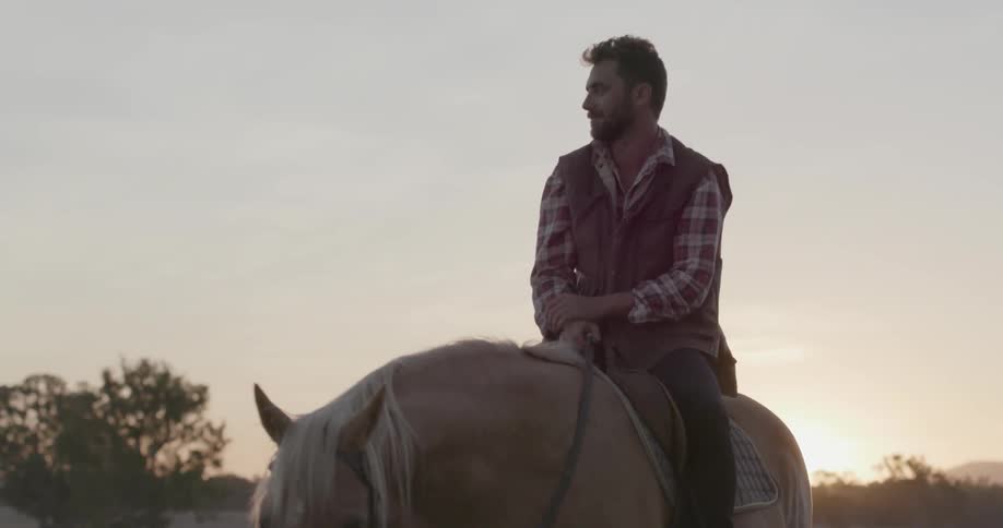 Man sitting on a horse that is drinking out of a trough