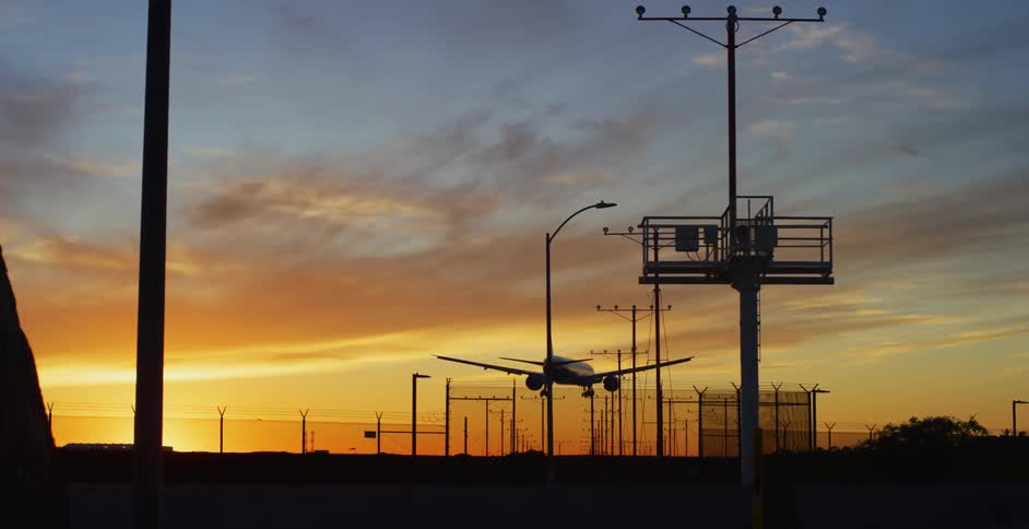 An airplane lands at an airport at sunset