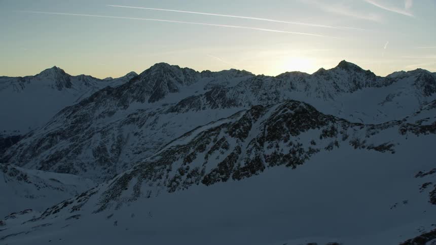Sun rises over snow covered mountains