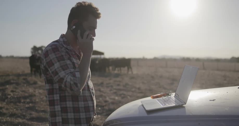 A man talks on the phone while working on a ranch