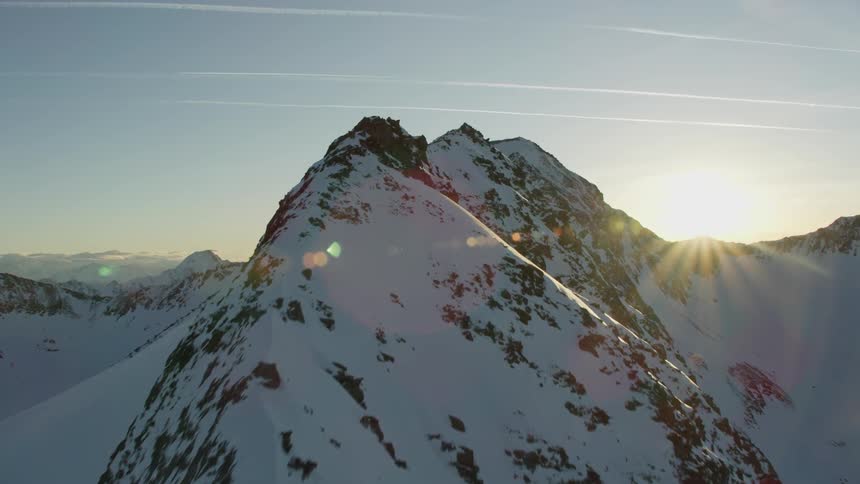 The sun shines over a snowy mountain ridge