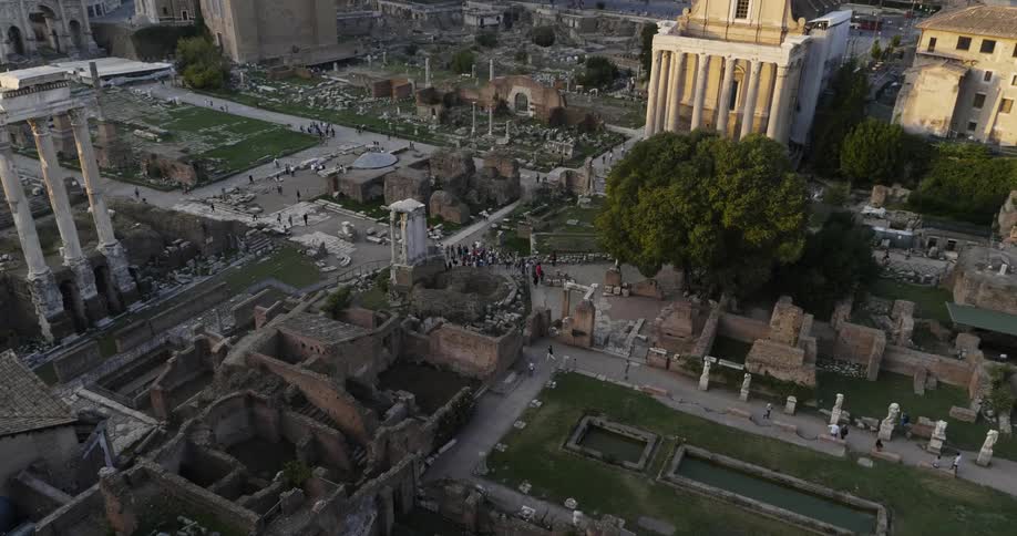 People walk near stone ruins in a city