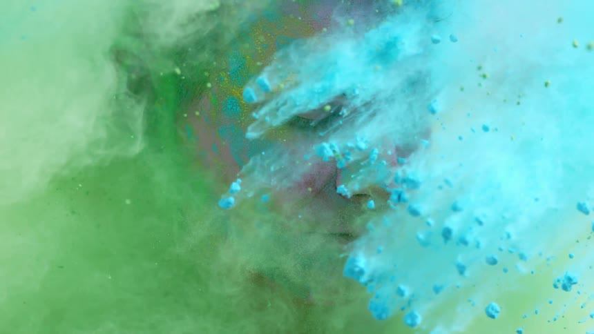 A man closes his eyes as colored dirt hits his face