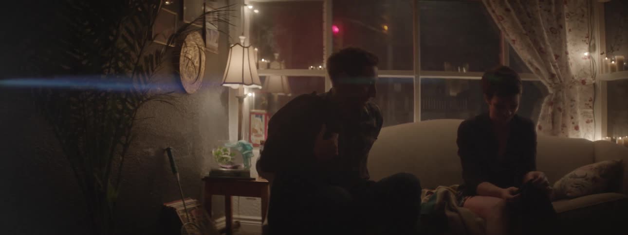 A man and woman sit on the couch talking