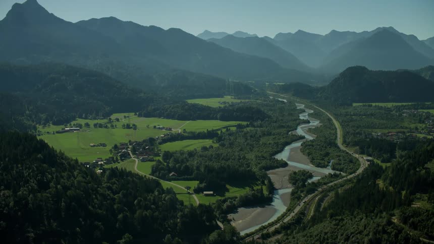 Cars travel on a road winding through a mountain valley