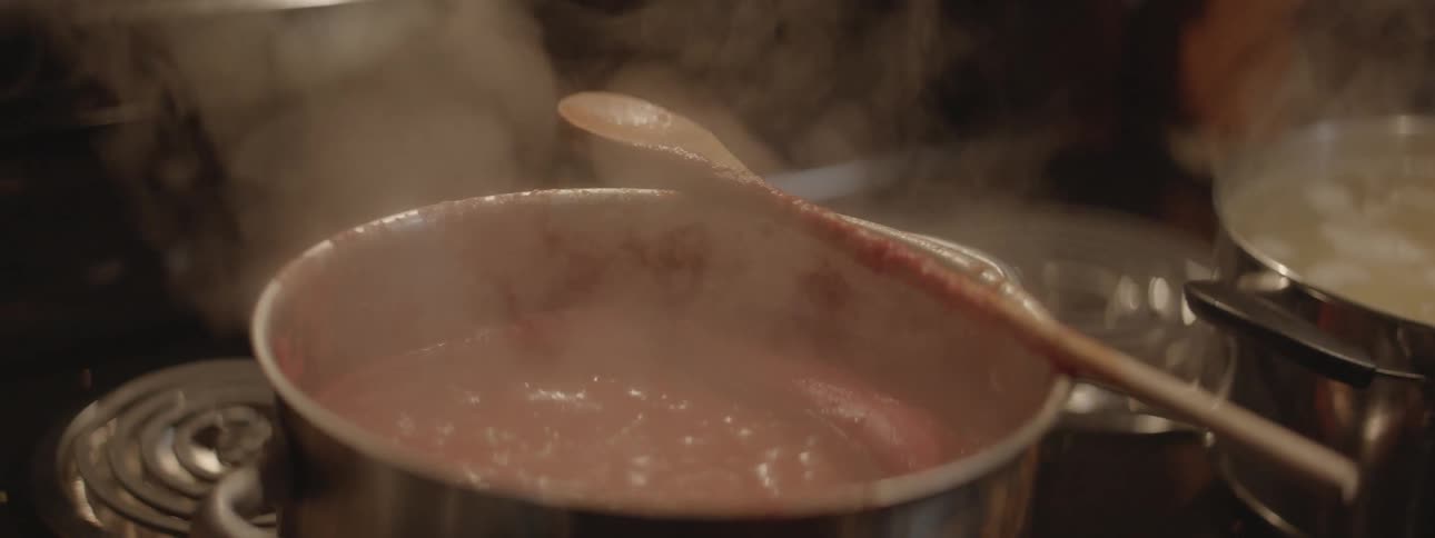 Sauce bubbling and steaming in pot on stove in kitchen
