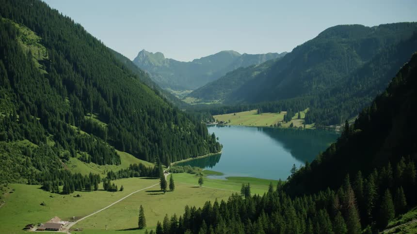 The mountains lead down to a single house by a lake