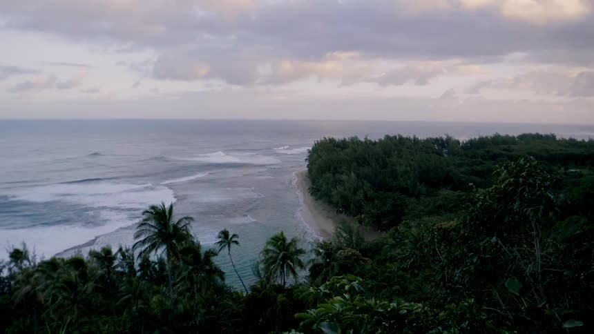 Waves roll onto a tropical island shore at dusk
