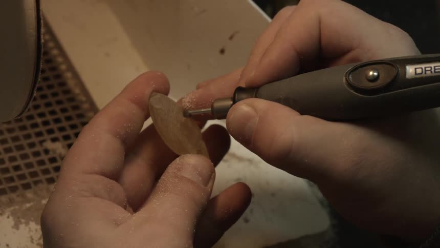 A person uses a tool to carve into a stone