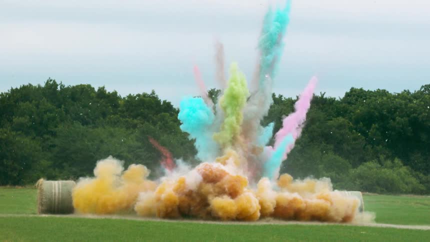 A large explosion on the field gives off colored dirt and a shock wave