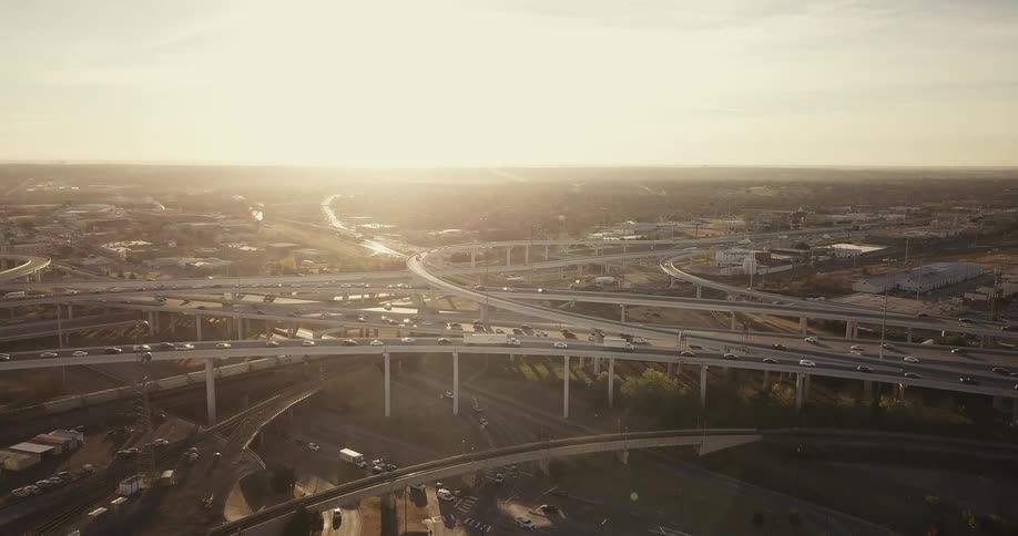 Cars drive on a city highway at sunset