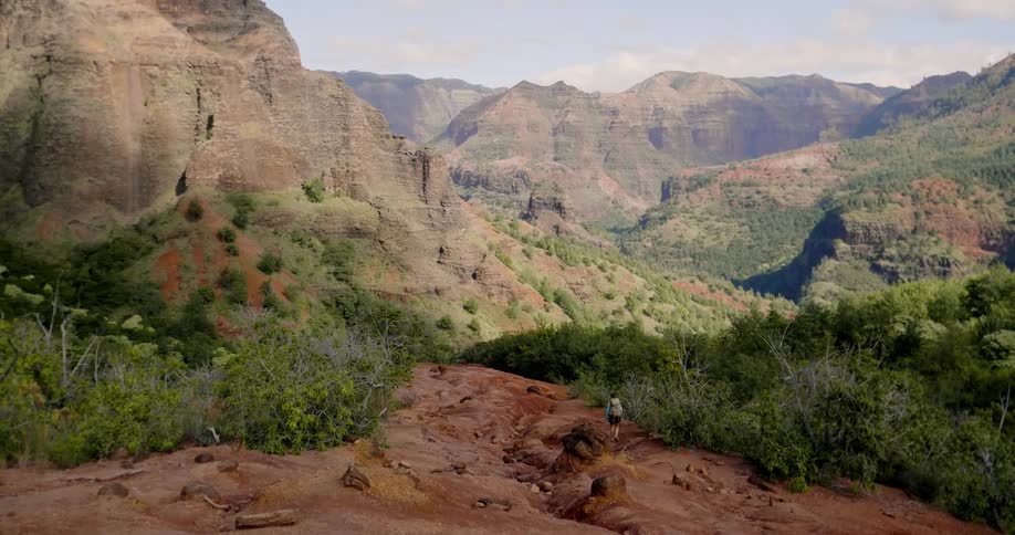 Person walks on rocky terrain through the mountains