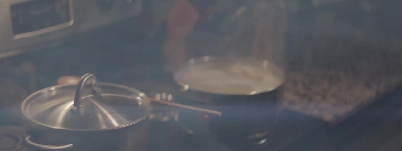 A man checks on his pots of cooking food then kisses a woman