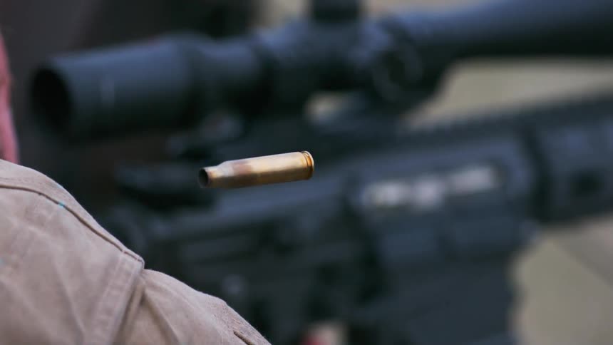 A bullet casing flies through the air as a gun is fired