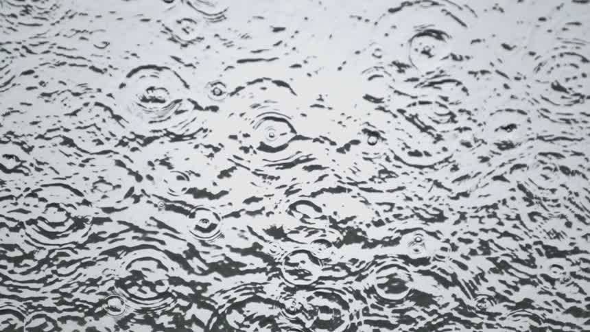 The pool of water has rain dropping steadily