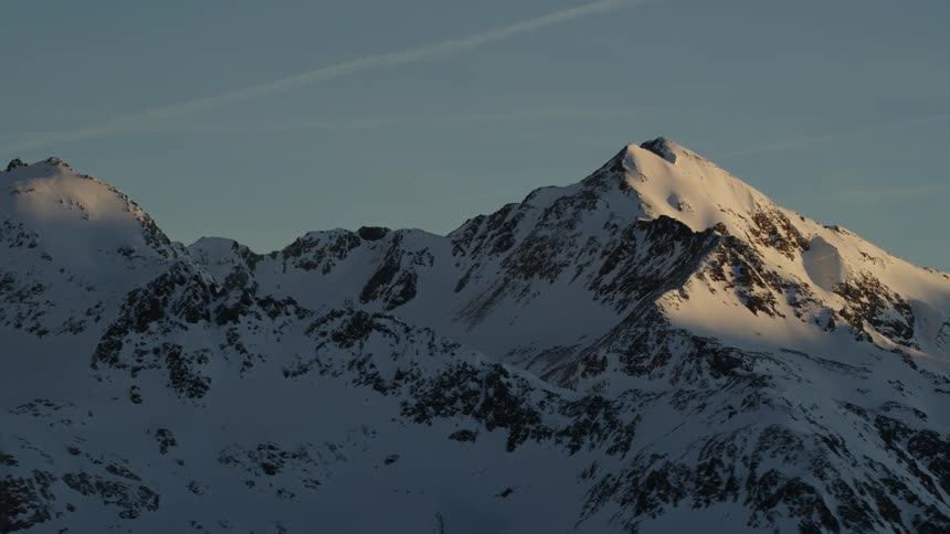 The sun shines on snow covered mountain peaks