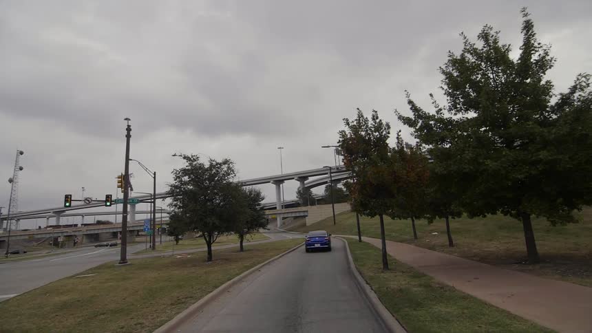 A car travels up on on-ramp toward a freeway during the day
