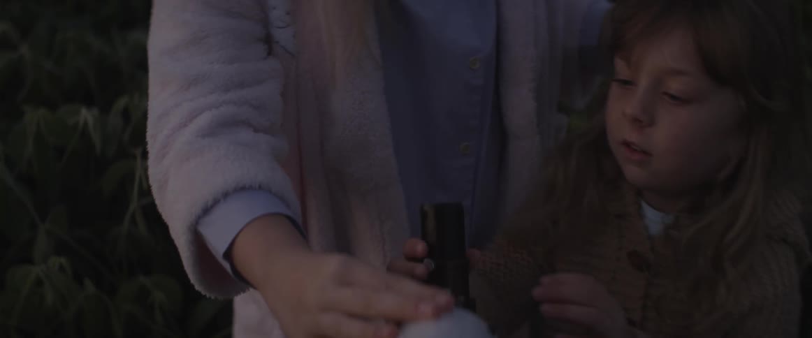 Woman looks through a telescope and waves her hand and a child comes over to look through it