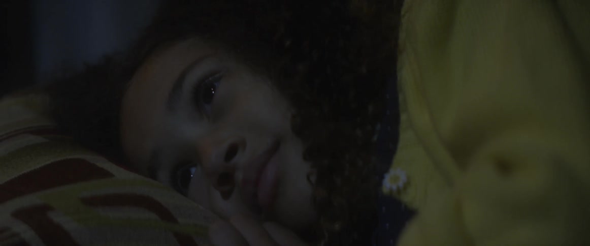 A girl smiles as she lays in bed