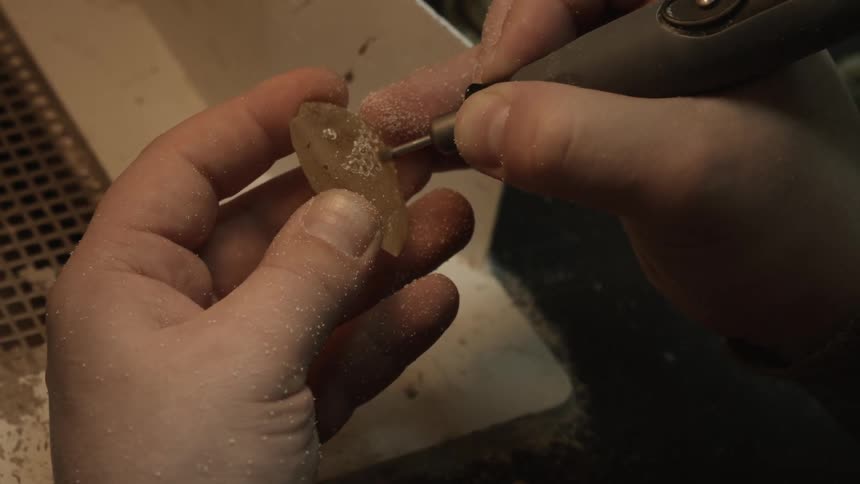 A man carves a yellow stone