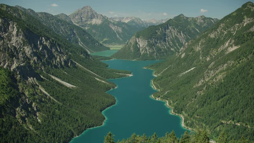 The mountain is covered with tall trees leading to a lake at the bottom