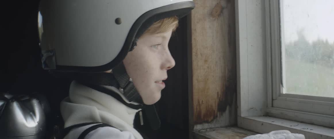 A red-headed boy looks out the window