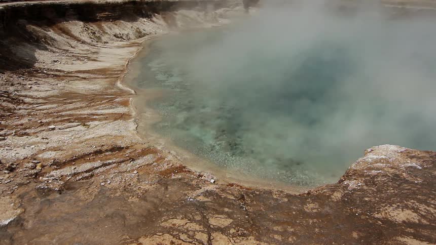 Steam rises from a rippling hot spring