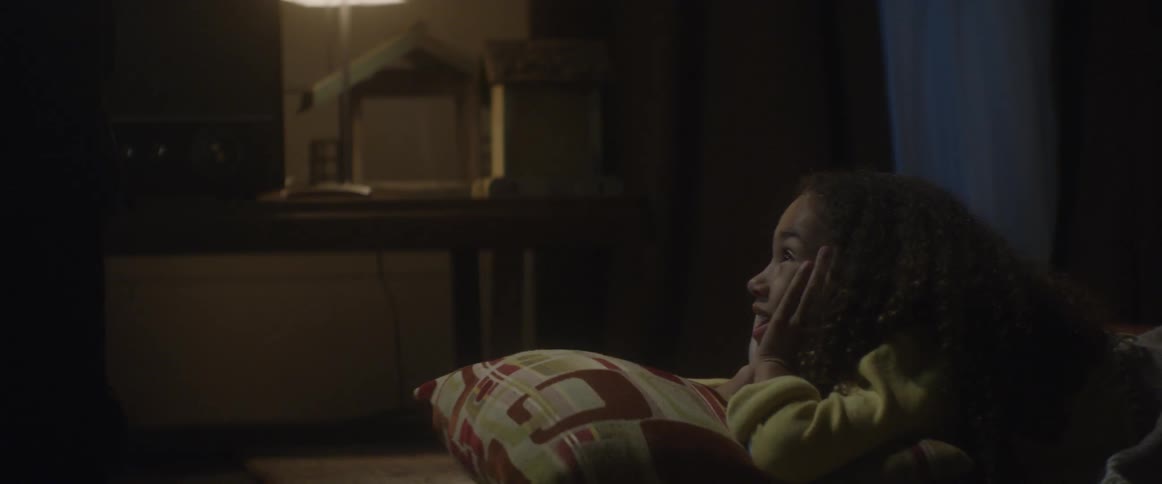 A girl with hands on her face smiles up at the tv